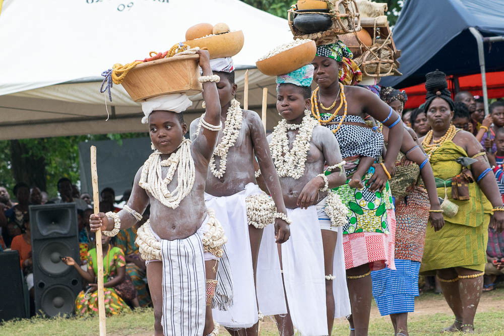 Young women in white cloth and beads carrying decorated bowls on their heads during the Hogbetsotso durbar procession at Anloga, Volta Region
